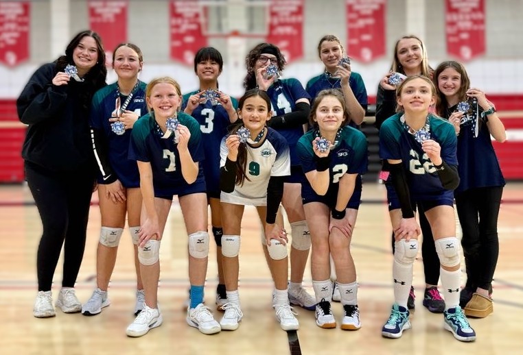 Team showing off the volleyball tournament medals they won.