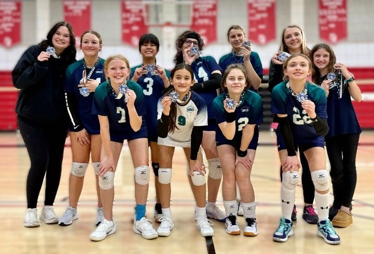 Team showing off the volleyball tournament medals they won.
