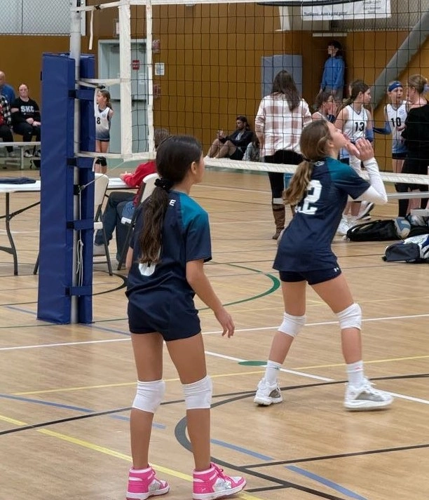 Girls in the middle of a volleyball game.